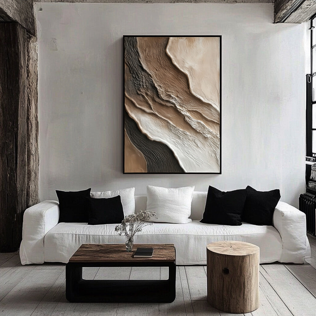 A framed abstract painting's warm tones create a central focal point, softening the high-contrast modern room with its white sofa and black pillows.