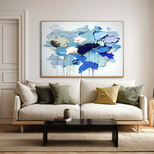 Abstract blue floral art over a modern white sofa with green and yellow pillows. Enhancing cozy living room decor.