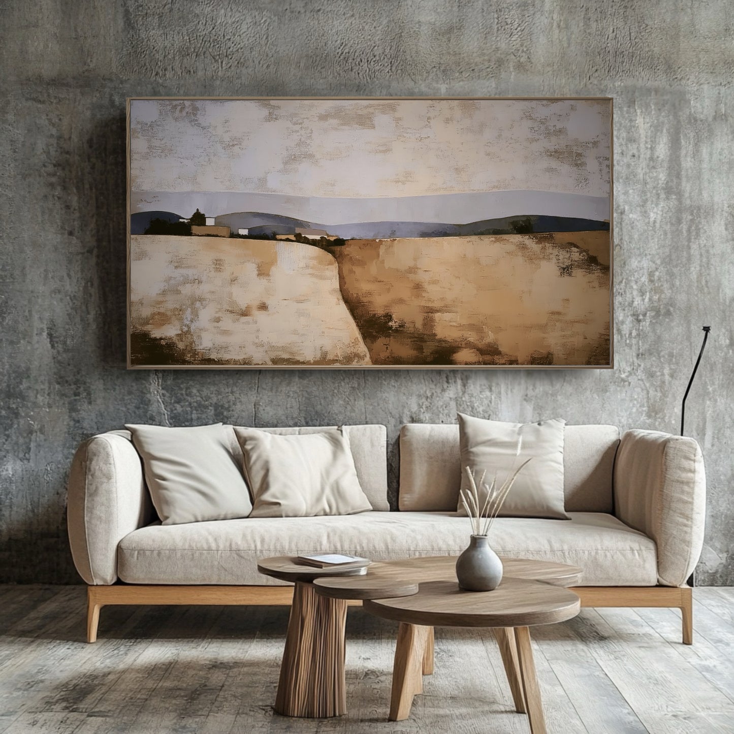 Earth-toned original landscape painting softens a dramatic industrial concrete wall above a minimalist neutral sofa and wood tables.