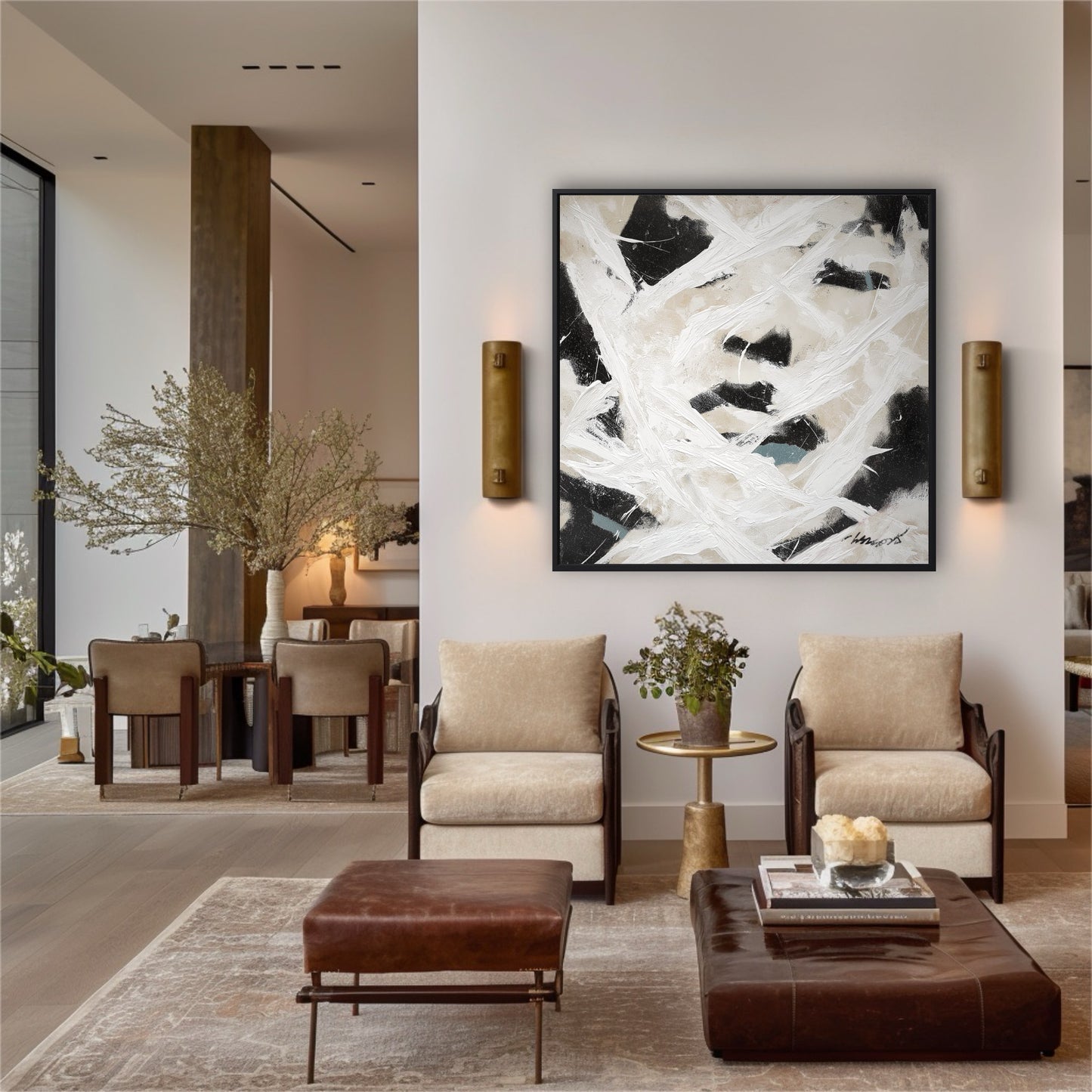 Large abstract painting on a white wall in a modern living room with beige armchairs and brown leather ottomans.