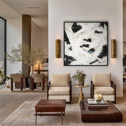 Large abstract painting on a white wall in a modern living room with beige armchairs and brown leather ottomans.