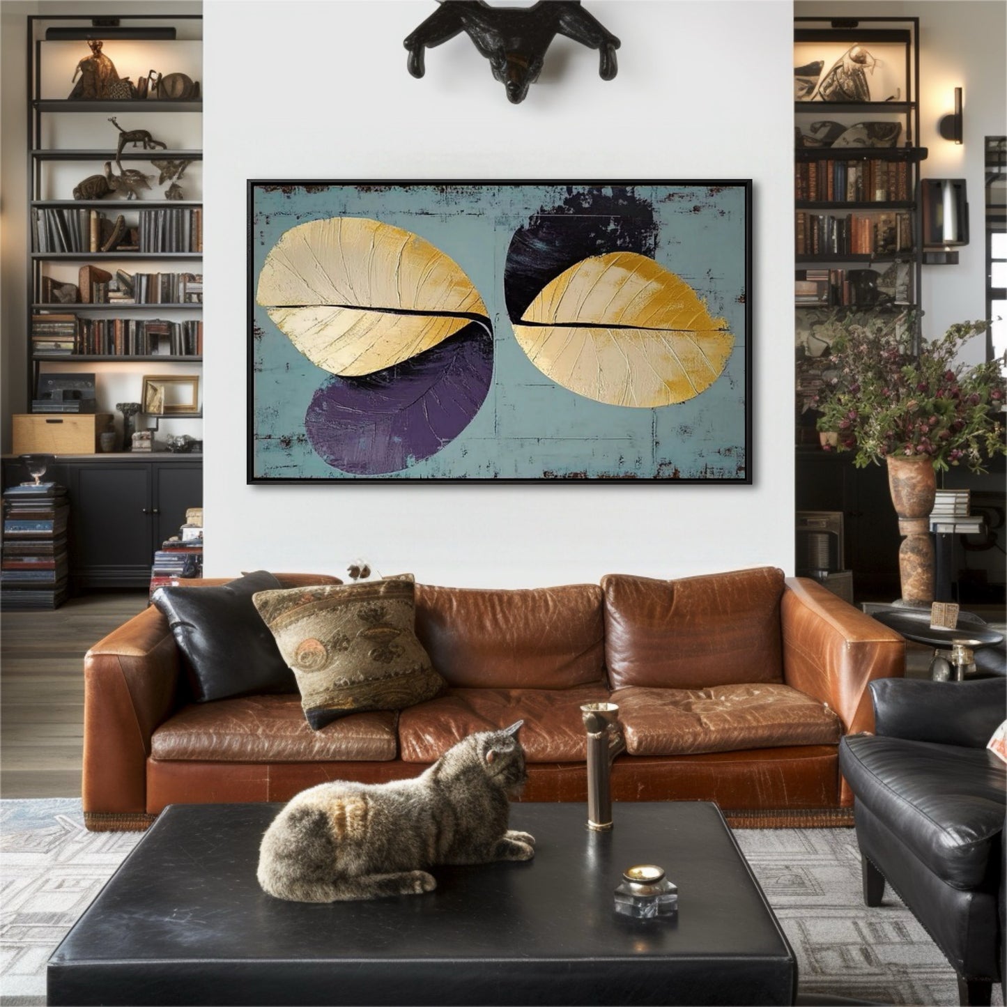 Abstract gold leaf art adds a modern color accent to an eclectic study, contrasting with the brown leather sofa and dark bookshelves.