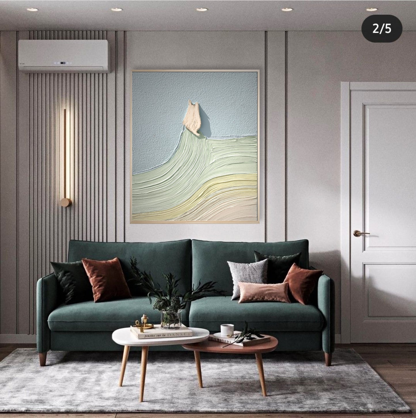 Original textured art with pale blue and green sits above a dark green sofa, offering bright, cool color contrast in a modern interior.