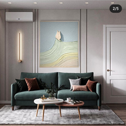 Original textured art with pale blue and green sits above a dark green sofa, offering bright, cool color contrast in a modern interior.