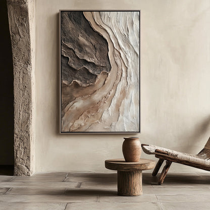 A large vertical textured painting in warm neutrals complements a rustic, wabi-sabi room with stone floors and a wooden stool.