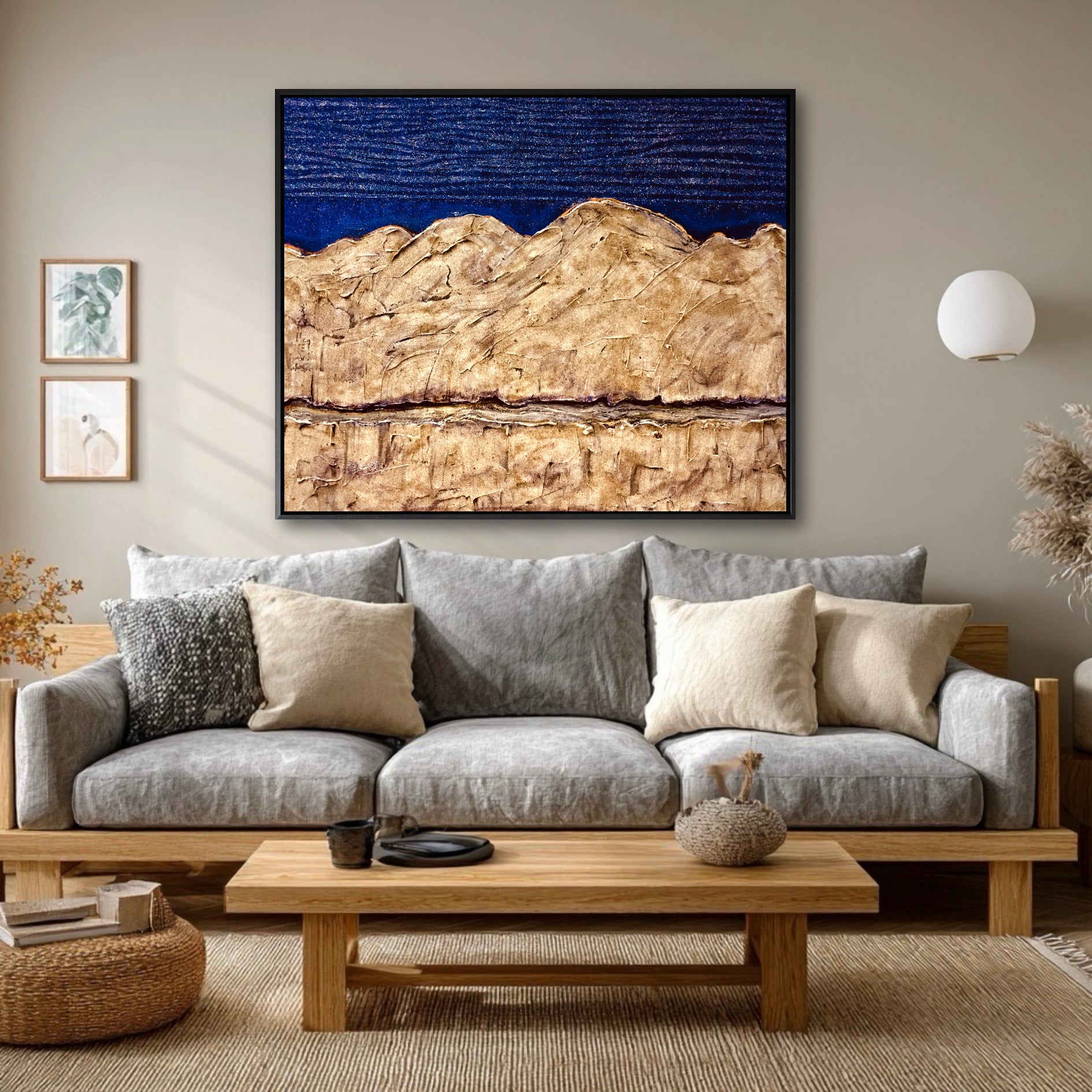 A large abstract blue and gold painting hangs as a colorful focal point above a gray sofa in a neutral, Scandinavian-style living room.