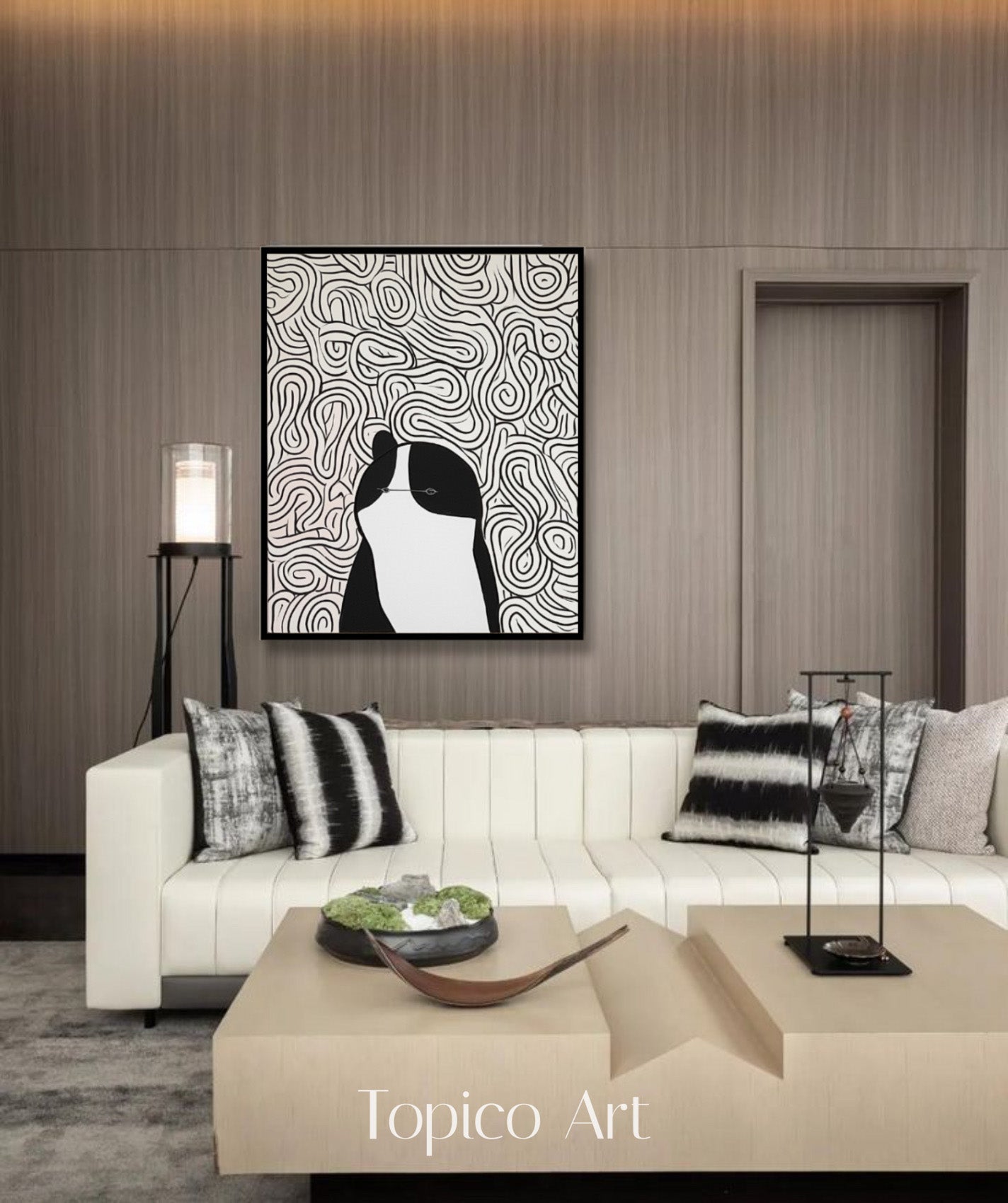 Black and white scribble cat art enhancing a creamy white couch and wood-paneled walls, perfect for a high-end, contemporary setting.