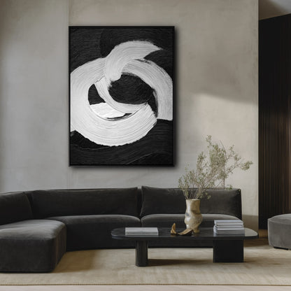 Large black and white abstract painting on a plaster wall over a dark velvet sectional sofa in a moody minimalist room.
