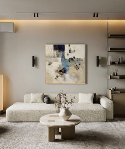 Abstract artwork adds depth to a minimalist, Scandinavian-style lounge; its light neutral tones harmonize with the beige textured sofa and streamlined built-in shelving.