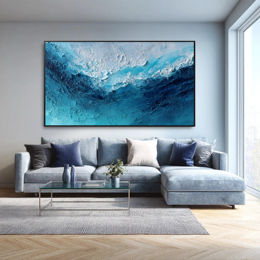 The large abstract ocean painting's blue and white tones perfectly complement the modern blue sectional and cool-toned living room.