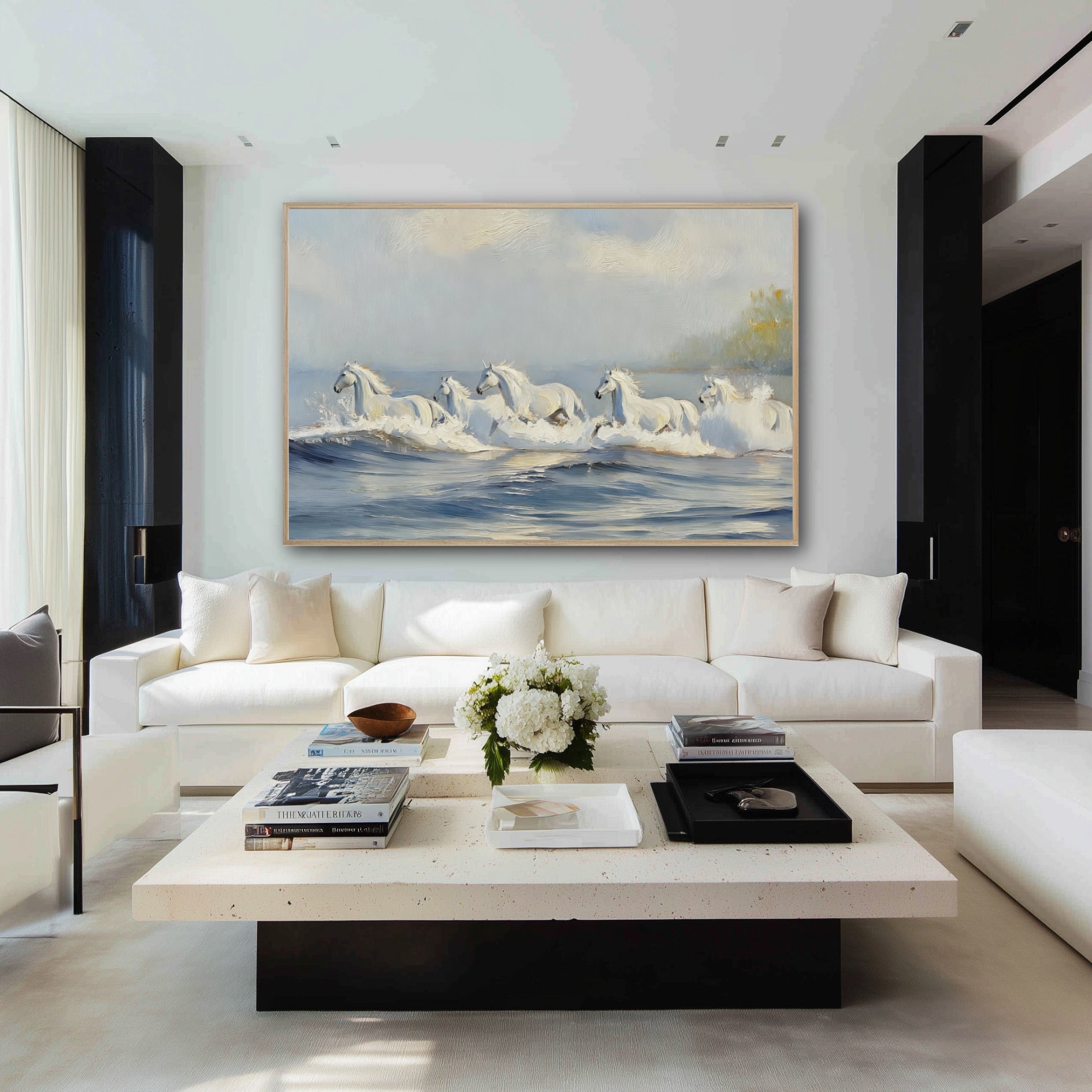 A large horse and ocean painting hangs above a long white sofa in a stark, modern black and white living room.