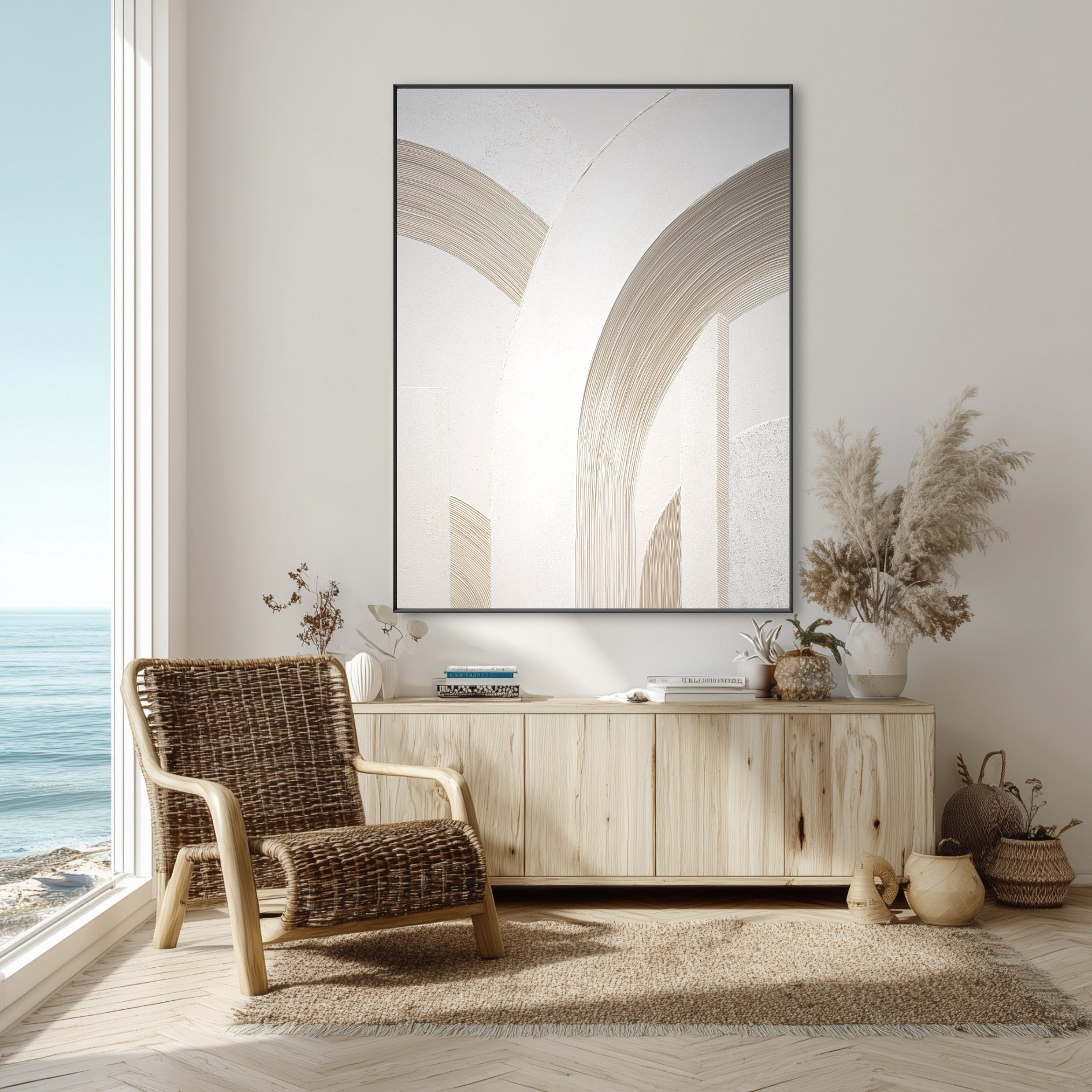 Large architectural abstract art in a coastal living room with a rattan chair, wood credenza, and an ocean view.