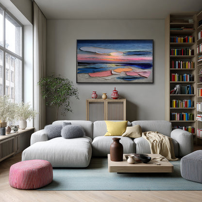 Textured sunset painting over a large gray sectional sofa in a cozy, contemporary room with full wall bookshelves and bright natural light.