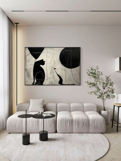 Abstract cat silhouettes provide a strong focal point over a clean, contemporary sofa with black accents in a bright, modern apartment.