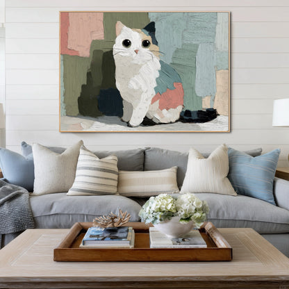 Thick impasto cat painting anchors a coastal living room with white shiplap walls, a grey sectional, and a wooden tray on the coffee table.