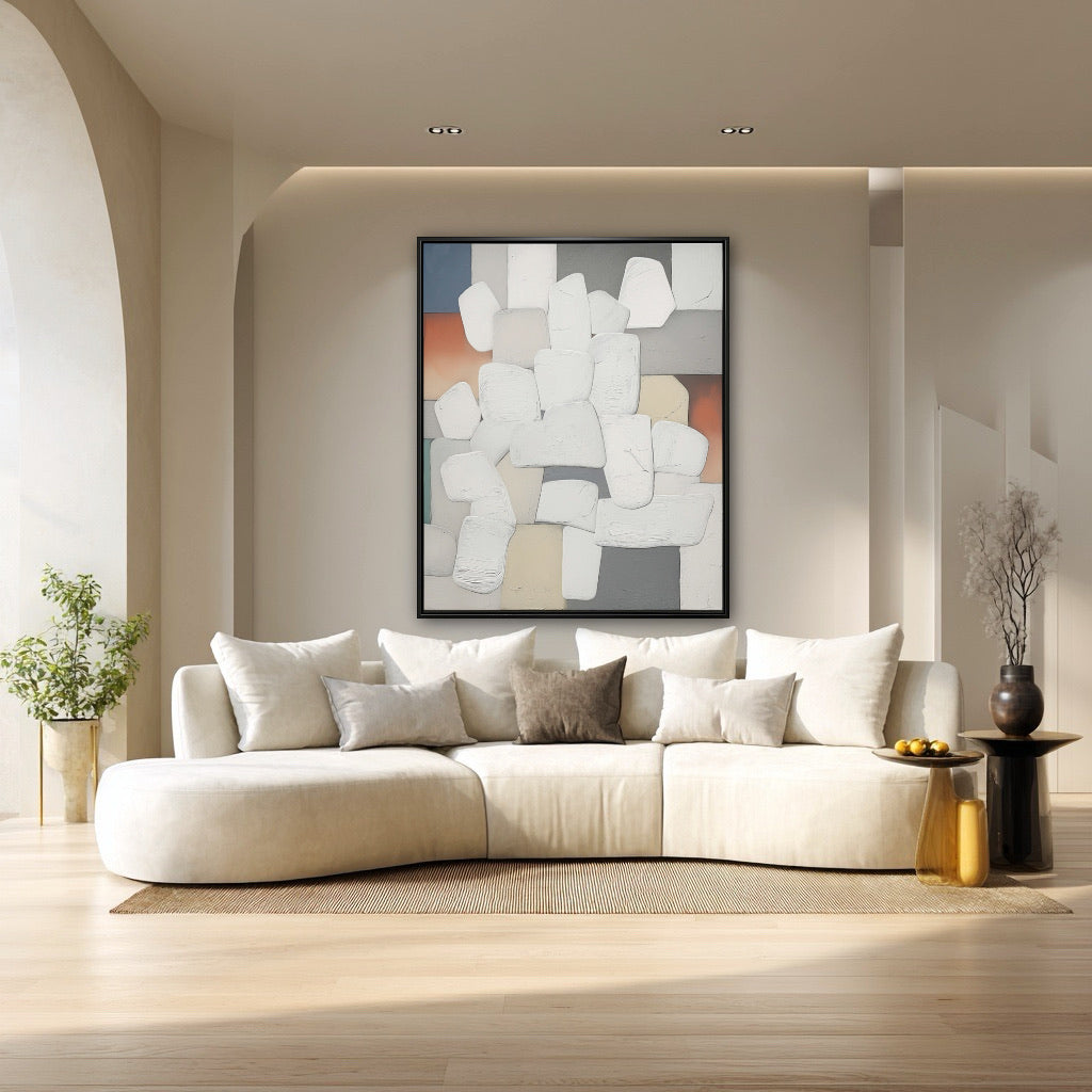 Modern living room with a white sofa, abstract painting, and decorative items.