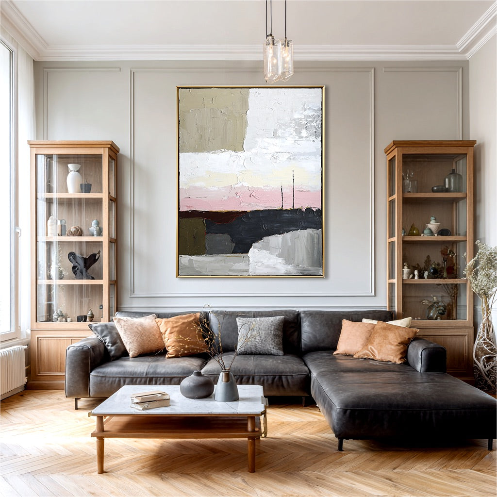 Abstract painting in a classic room with grey wall panels, dark leather chaise, and matching wood display cabinets.