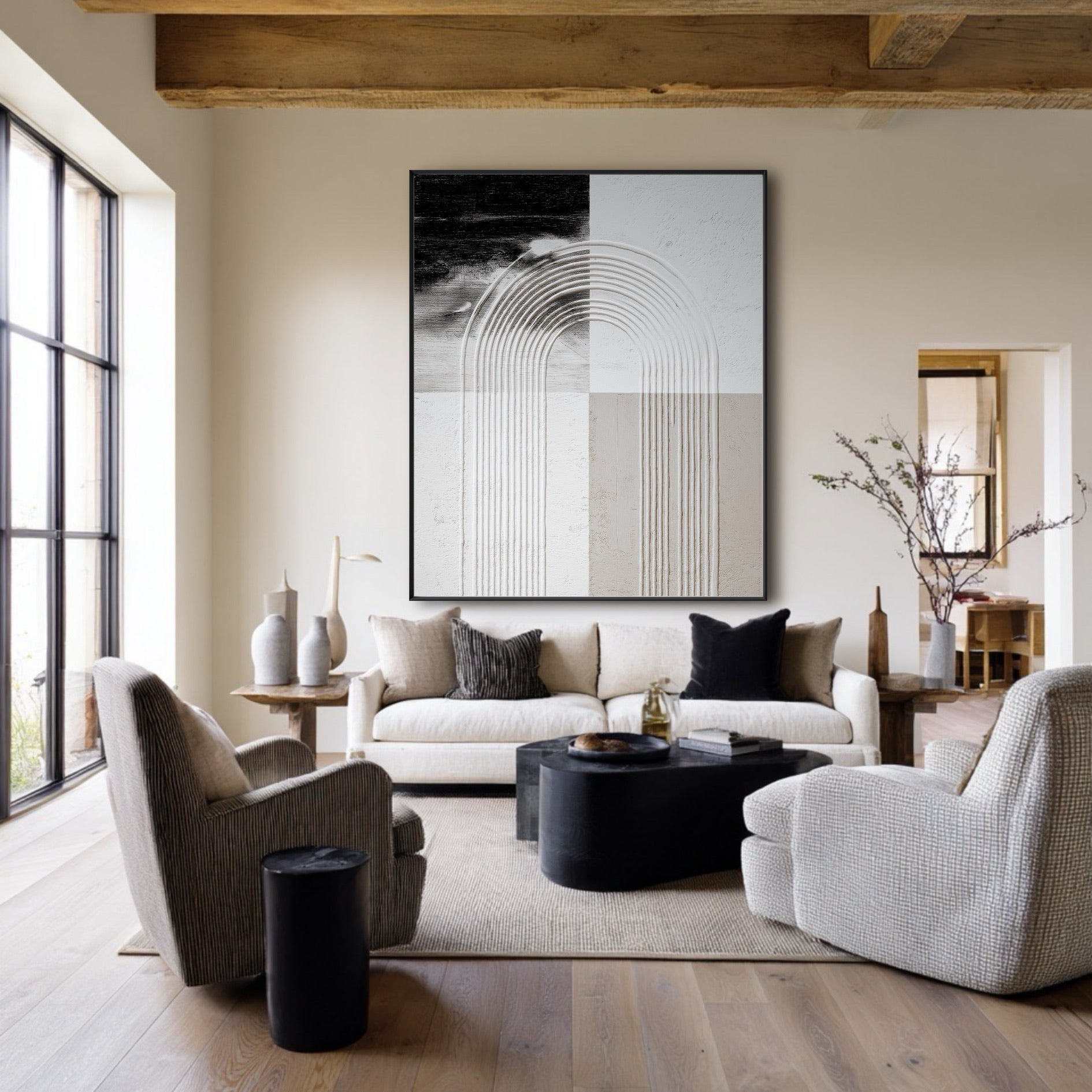 Large abstract geometric art hangs in a rustic modern living room with exposed wood beams, a white sofa, and grey armchairs.