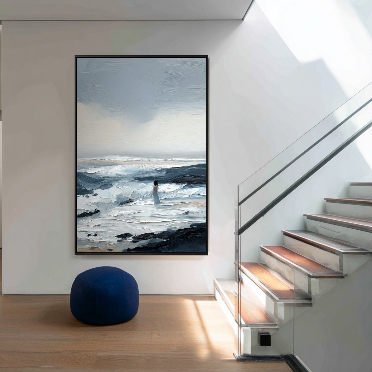 A large vertical painting serves as a dramatic focal point in a modern hallway, its blue tones echoed by the pouf near the stairs.