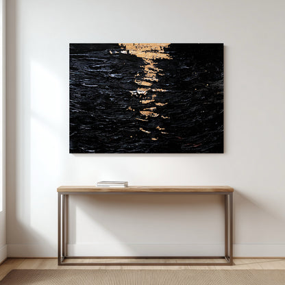 A large black and gold abstract painting hangs on a white wall in a minimalist hallway, centered above a simple wood console table.