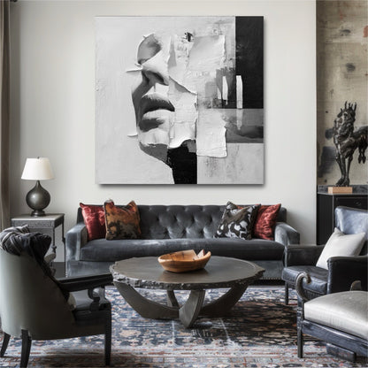 Modern black and white face painting above a grey tufted sofa in an eclectic living room with a patterned rug and metal table.