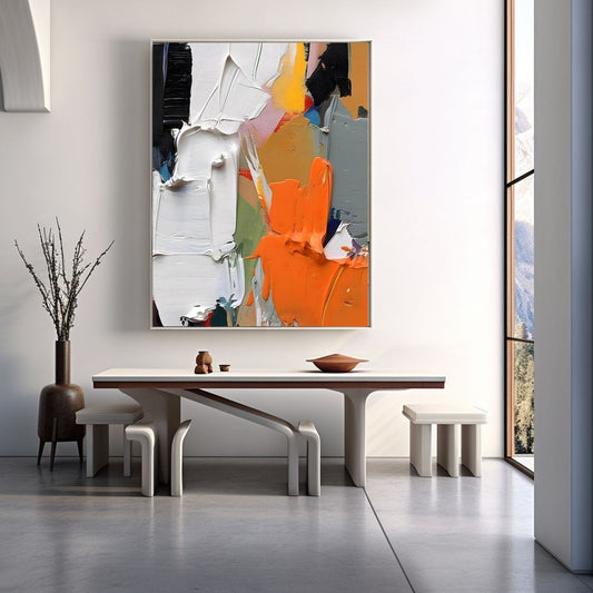 Vibrant orange art enhances a clean, modern dining space with a white sculptural table and a tall panoramic window.