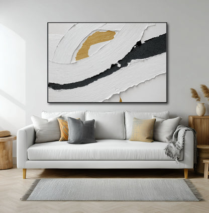 Large black, white, and gold abstract art hanging over a modern white sofa in a bright, contemporary living room.