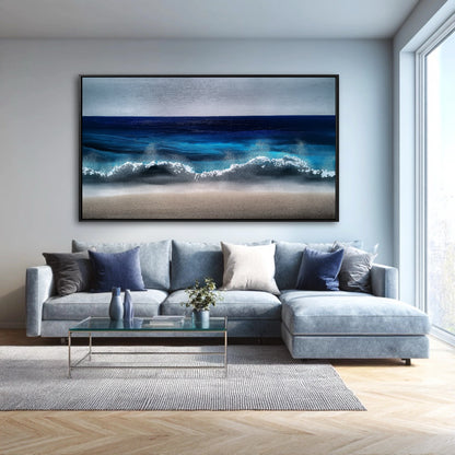 A large, modern blue ocean painting hangs above a light blue-gray sectional sofa in a bright, contemporary living room.