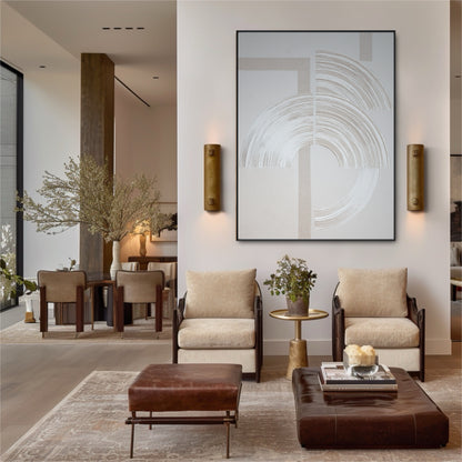 Large abstract painting with sweeping lines in an elegant living room with leather furniture and brass wall sconces.