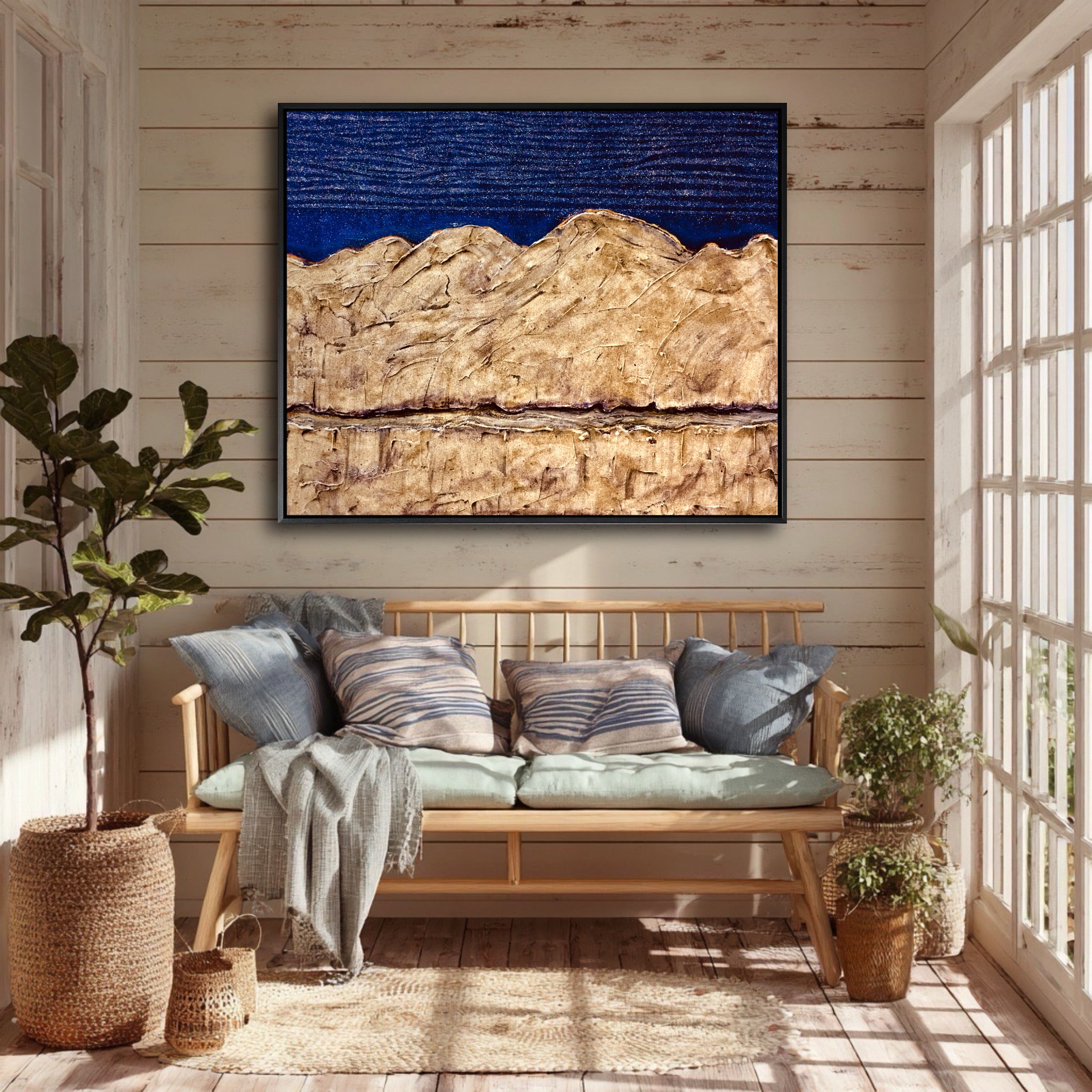 A blue and gold abstract landscape painting hangs on a wood-paneled wall, unifying the colors of a cozy, plant-filled sunroom.