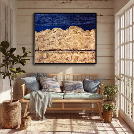 A blue and gold abstract landscape painting hangs on a wood-paneled wall, unifying the colors of a cozy, plant-filled sunroom.