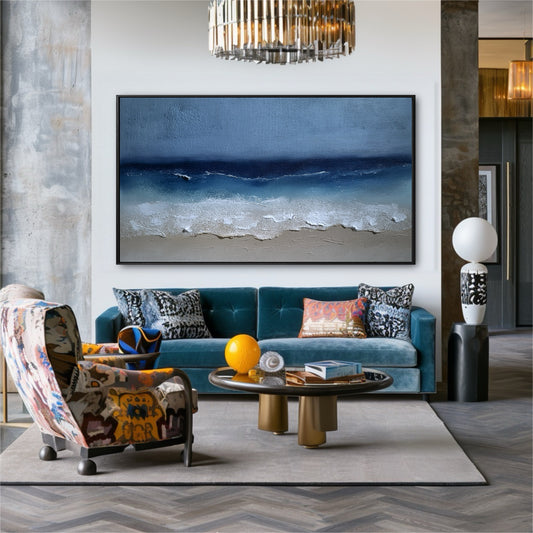 The large beach painting acts as a serene anchor in a bold, eclectic room, its blue hues complementing the velvet sofa and patterned chair.