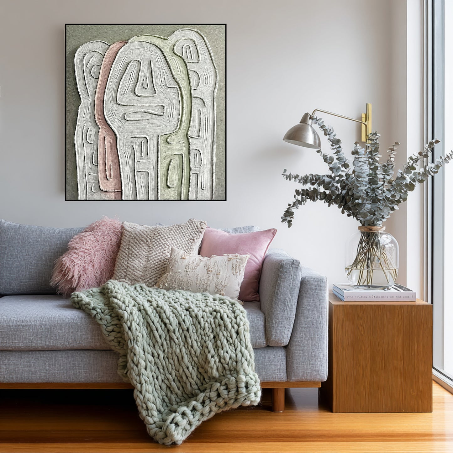 Soft-toned abstract painting over a cozy gray sofa draped with a chunky knit blanket in a bright, hygge-style space.