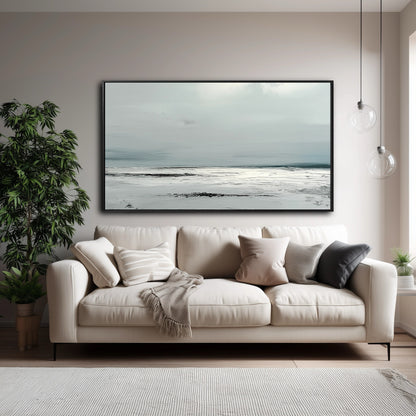 A large, textured abstract seascape hangs over a beige sofa in a modern, neutral-toned living room with a large houseplant.