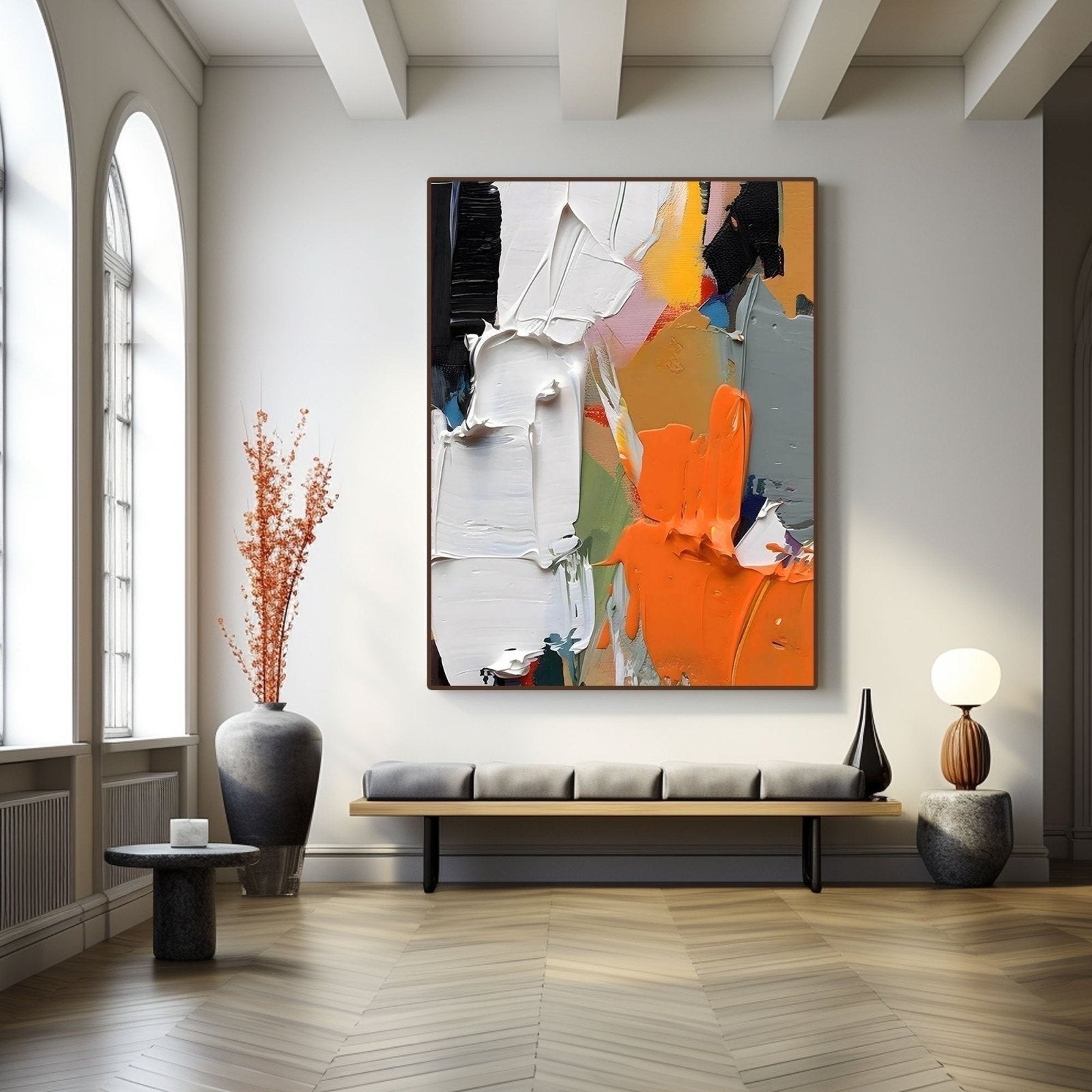 Textured abstract art providing a bold focal point over a low bench in a minimalist hall with elegant arched windows.