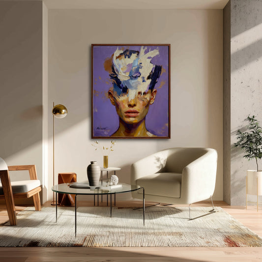 A large framed portrait painting hanging in a sunlit corner of a modern living room with a beige armchair and glass table.