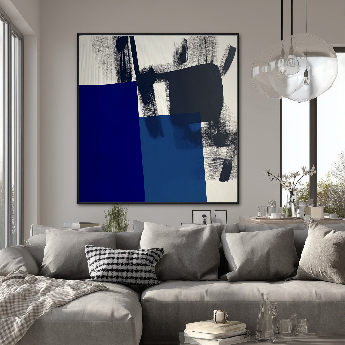 Large abstract art piece centered above a gray sectional, adding a punch of deep blue color to a light-filled contemporary dining/living area.
