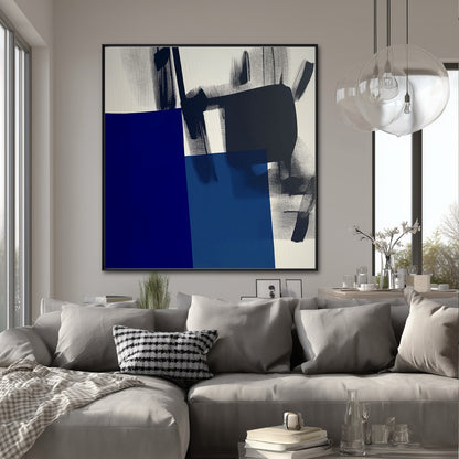 Large abstract art piece centered above a gray sectional, adding a punch of deep blue color to a light-filled contemporary dining/living area.