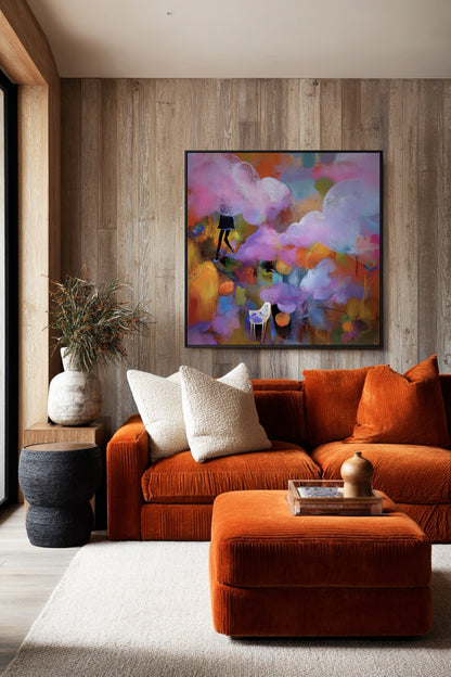 Vibrant original abstract art provides a strong color contrast in a rustic, bohemian living room; warm wood paneling and a bold orange velvet sofa amplify its energy.