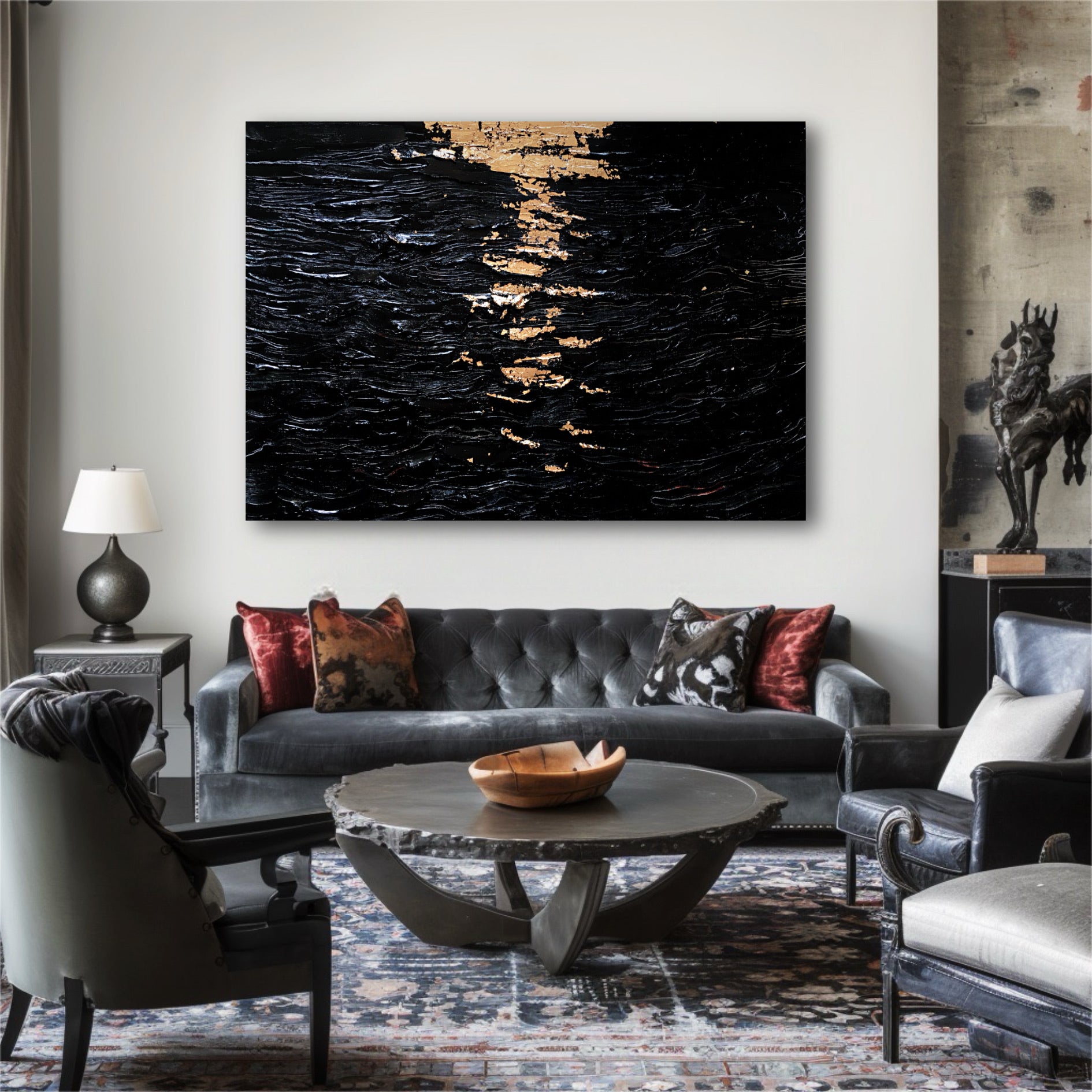 A black and gold textured painting hangs in a luxurious, eclectic living room, centered above a gray tufted velvet sofa.