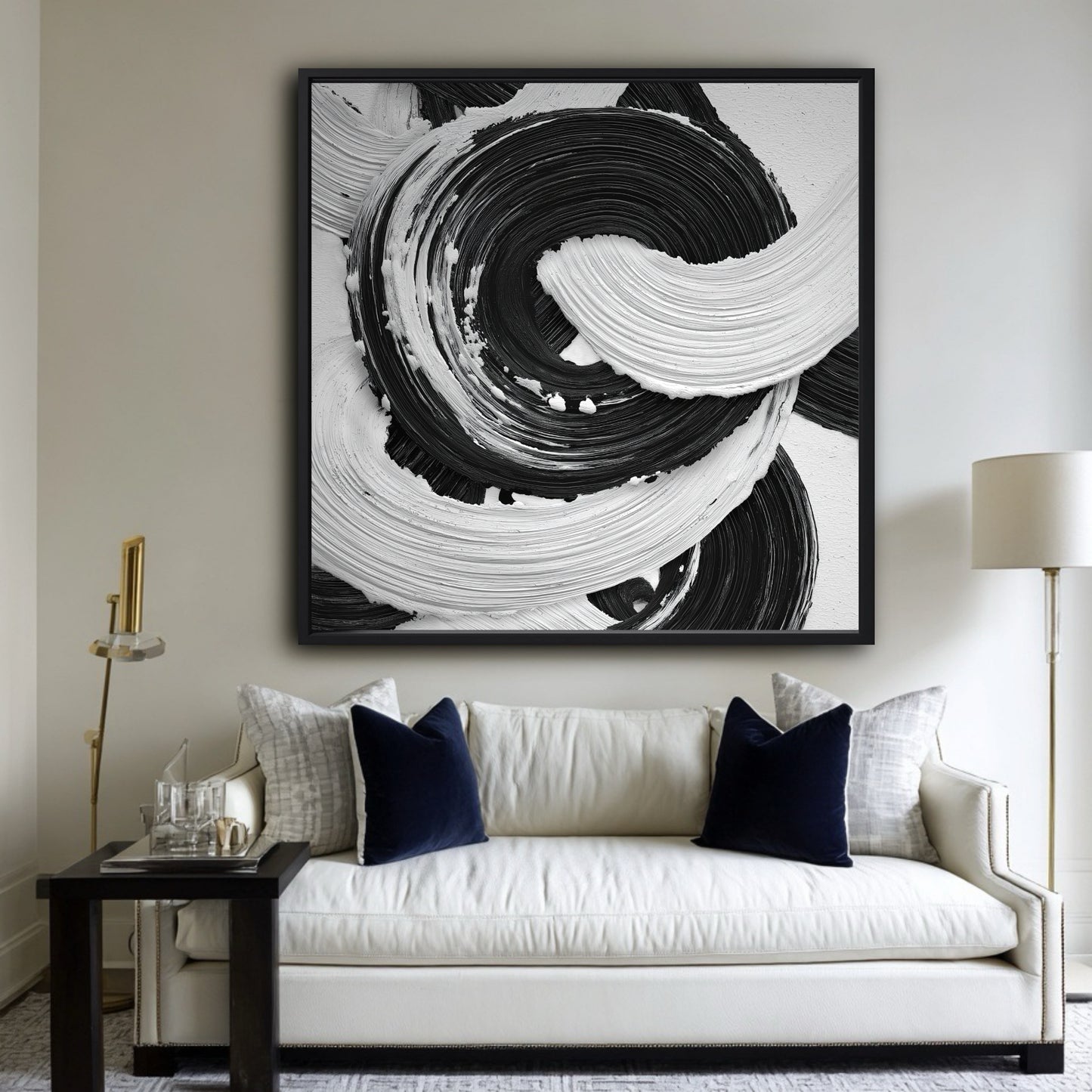 Large black and white abstract painting above a classic white sofa with navy blue velvet pillows in a living room.