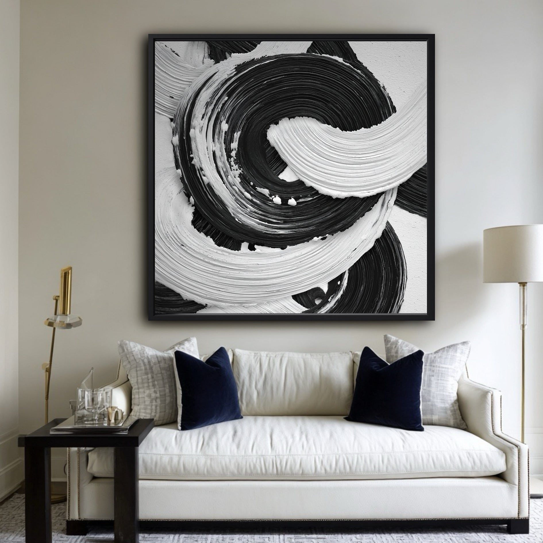 Large black and white abstract painting above a classic white sofa with navy blue velvet pillows in a living room.