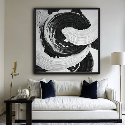 Large black and white abstract painting above a classic white sofa with navy blue velvet pillows in a living room.
