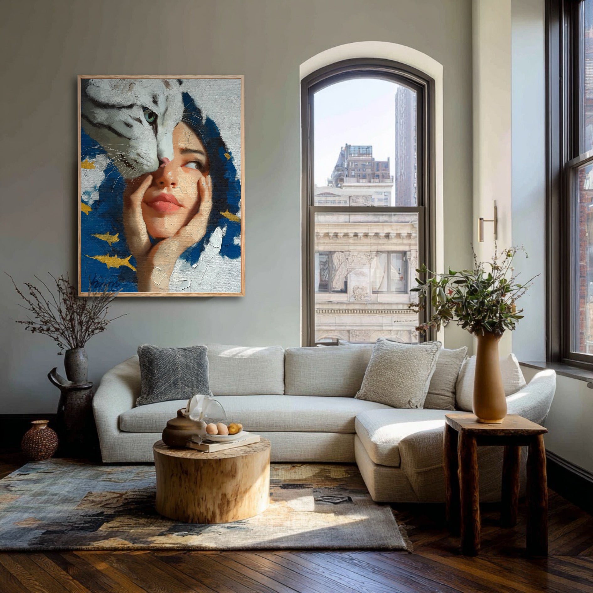 Surrealist painting of a woman and tiger hanging in a bright city loft with a large arched window and a beige sectional sofa.