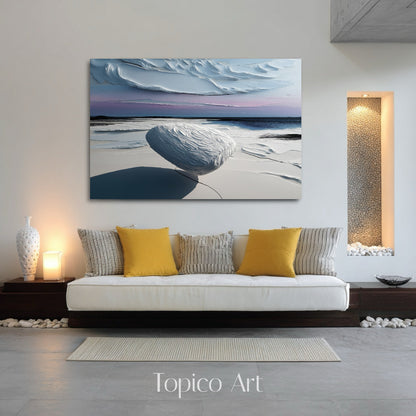 Cool abstract canvas over a low sofa with zen pebble detailing and warm accent lighting in a minimalist room.
