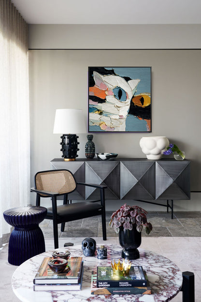 Impasto cat art over a gray geometric console, adding vibrant color and modern texture to a sophisticated, neutral-toned living space.