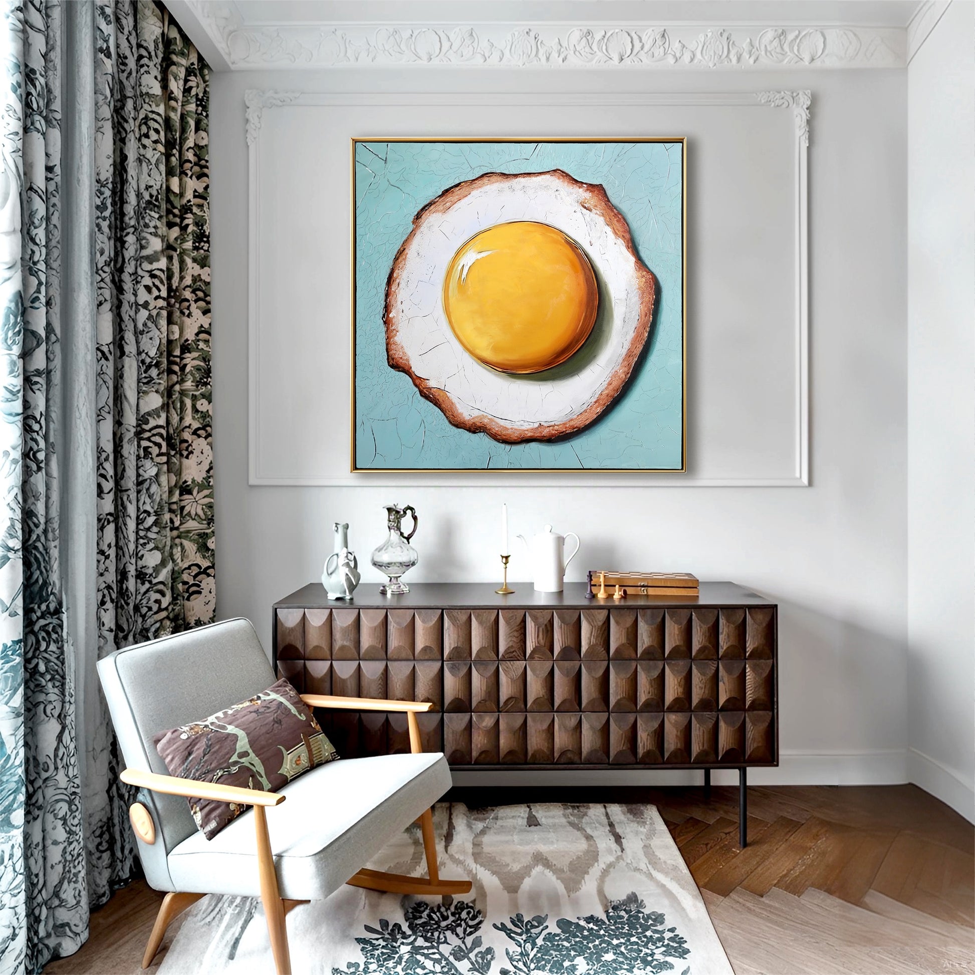 Framed fried egg art on gray paneled wall above wooden sideboard. Whimsical food painting adds color to elegant living room.