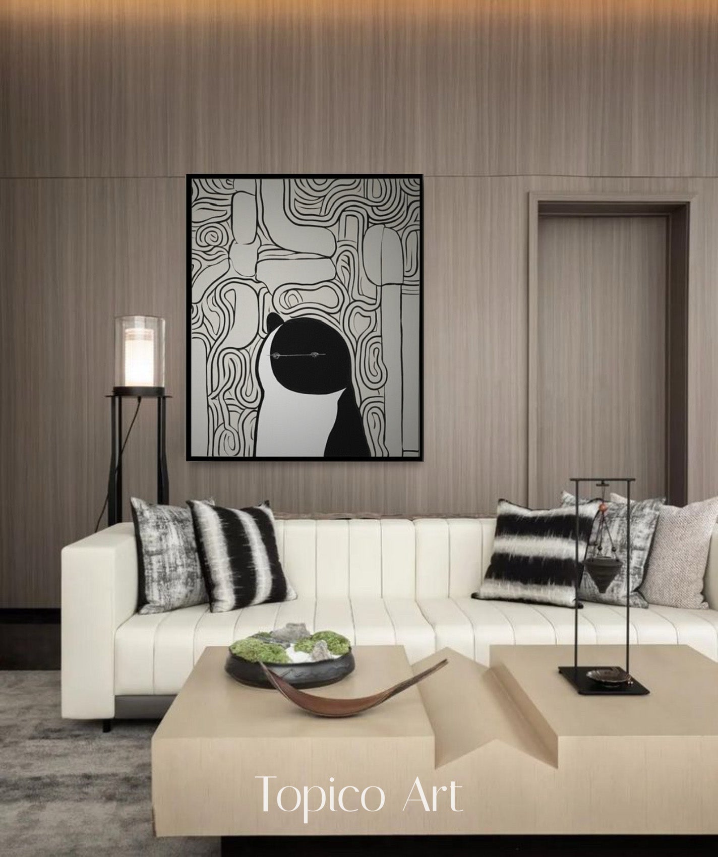 Black and white scribble cat art enhancing a creamy white couch and wood-paneled walls, perfect for a high-end, contemporary setting.