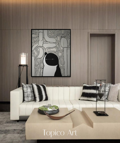 Black and white scribble cat art enhancing a creamy white couch and wood-paneled walls, perfect for a high-end, contemporary setting.
