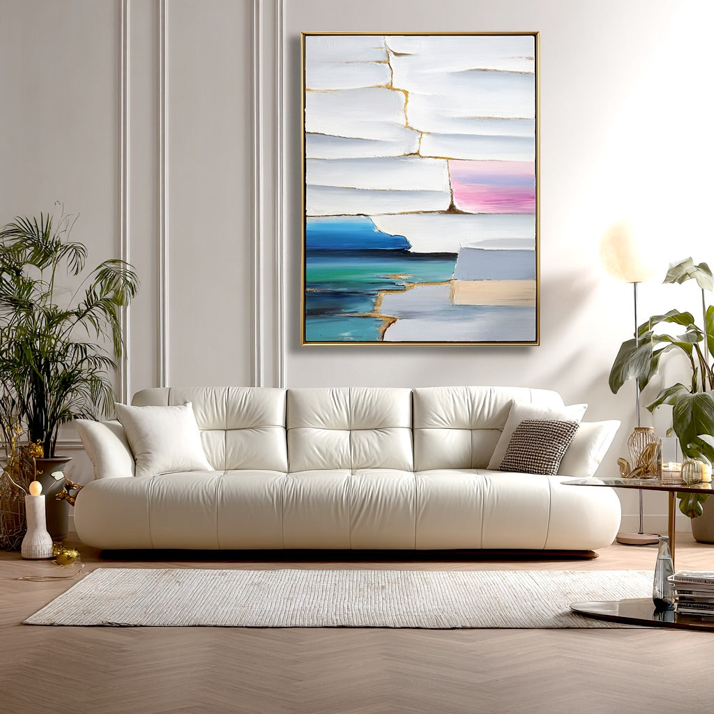 Modern living room with a white sofa, abstract painting, and decorative items.